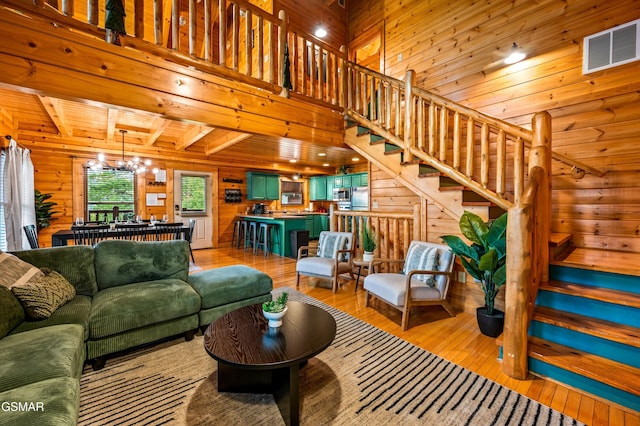 living area with an inviting chandelier, wooden walls, stairway, and light wood-style floors