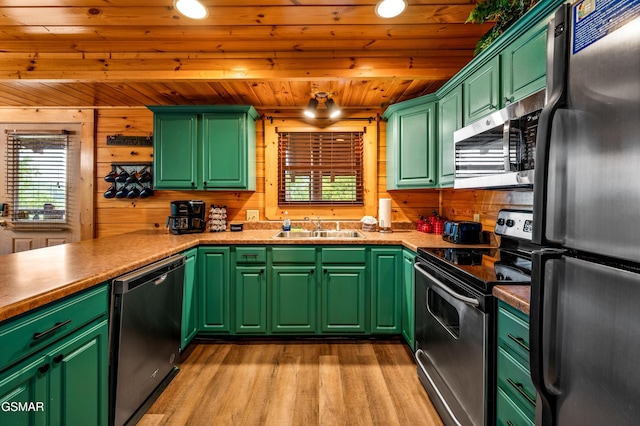 kitchen with a sink, wooden ceiling, wooden walls, and stainless steel appliances