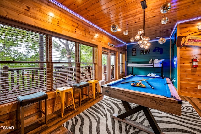 rec room featuring wooden walls, a chandelier, wood ceiling, wood finished floors, and billiards