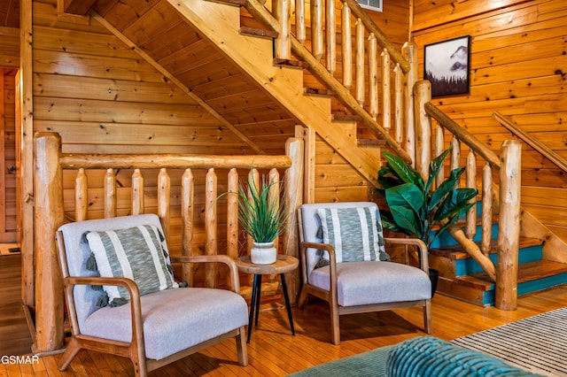 sitting room featuring lofted ceiling with beams, wooden walls, stairway, and wood-type flooring