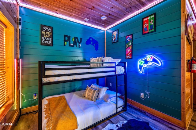 bedroom featuring baseboards, wood finished floors, and wooden ceiling