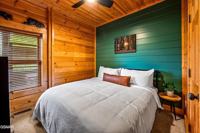 carpeted bedroom featuring wood ceiling, visible vents, wood walls, and ceiling fan