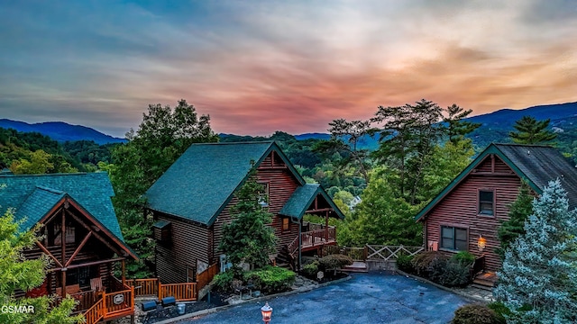 back of house featuring log exterior and a deck with mountain view