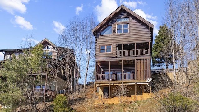 rear view of property with a balcony and log siding