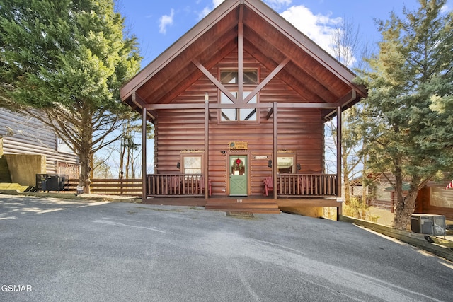 view of front of home with central air condition unit, fence, and log siding