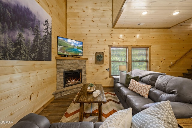 living room featuring wood-type flooring, a stone fireplace, and wood walls