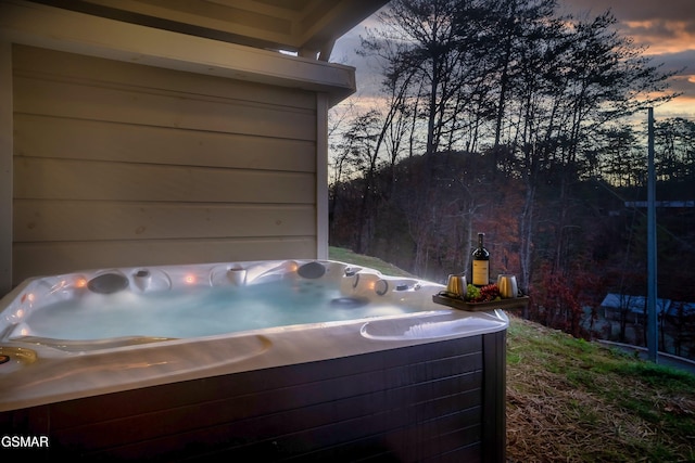 patio terrace at dusk featuring a hot tub