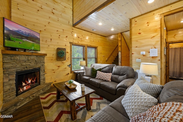 living room with wood ceiling, hardwood / wood-style floors, a stone fireplace, and wood walls