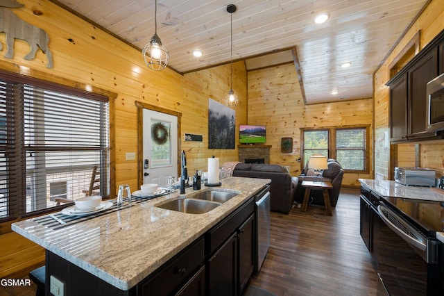 kitchen with pendant lighting, sink, stainless steel appliances, and a center island with sink