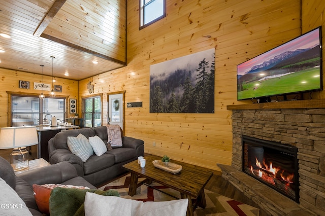 living room featuring wood ceiling, a stone fireplace, wooden walls, and a towering ceiling