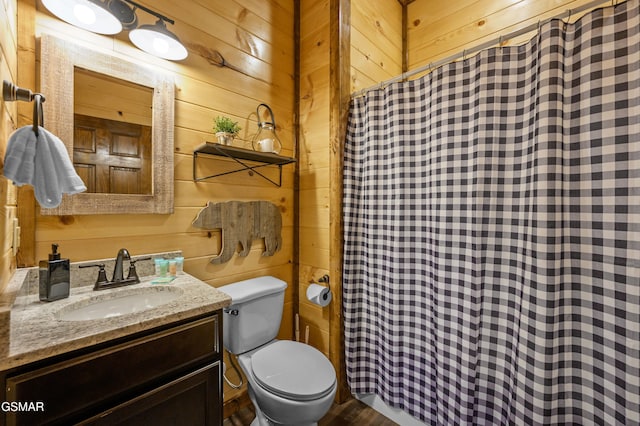 bathroom featuring vanity, toilet, and wood walls