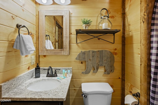 bathroom with vanity, wooden walls, and toilet