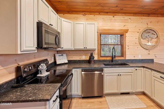 2229 Legend Dr, Sevierville, TN 37876 - kitchen featuring appliances with stainless steel finishes, wood ceiling, light wood-style floors, dark stone countertops, and wooden walls