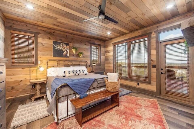 bedroom with ceiling fan, wooden ceiling, wood walls, access to outside, and hardwood / wood-style flooring