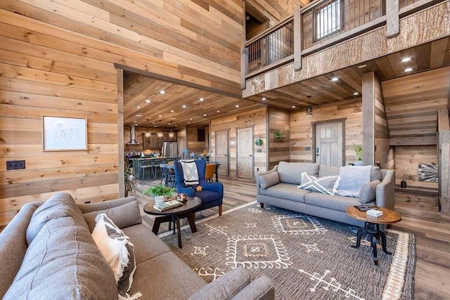 living room featuring wood walls, hardwood / wood-style floors, and a high ceiling