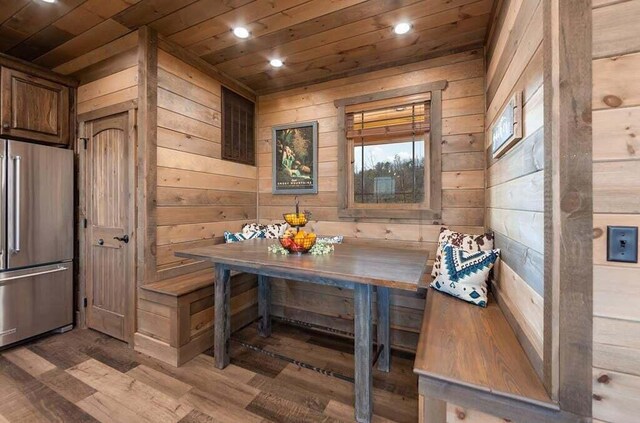 dining space featuring wood ceiling, wood walls, breakfast area, and hardwood / wood-style floors