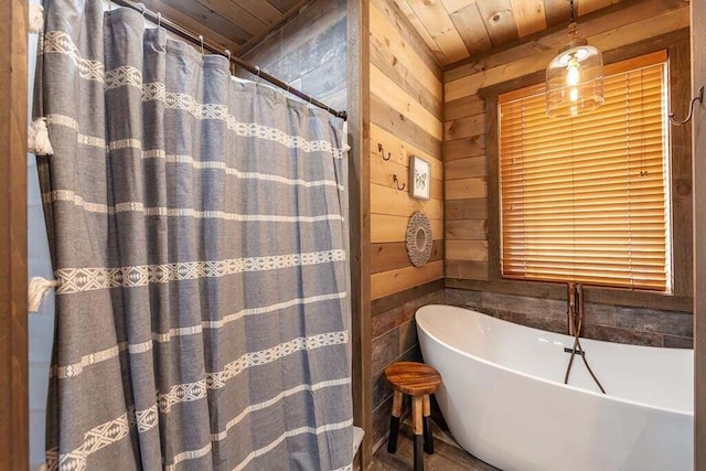 bathroom featuring a bathing tub, wood walls, and wood ceiling