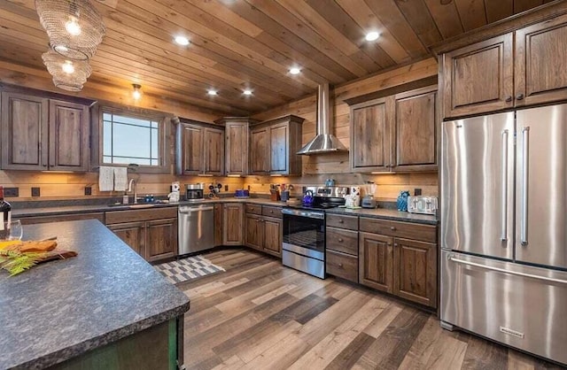 kitchen featuring appliances with stainless steel finishes, sink, dark hardwood / wood-style flooring, and wall chimney range hood