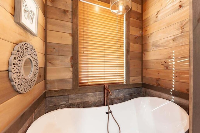 bathroom featuring a bathtub and wood walls