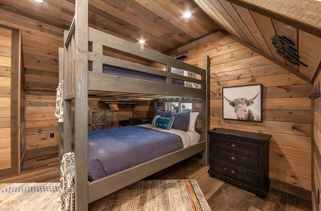 bedroom with wooden walls, light hardwood / wood-style floors, vaulted ceiling, and wooden ceiling