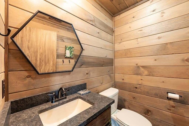 bathroom with wooden walls, vanity, and toilet