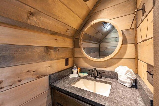 bathroom with wooden walls, vanity, wood ceiling, and lofted ceiling