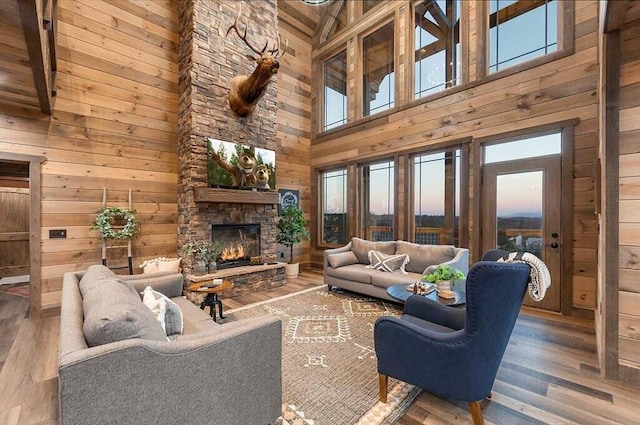 living room with wood walls, wood-type flooring, a fireplace, and high vaulted ceiling