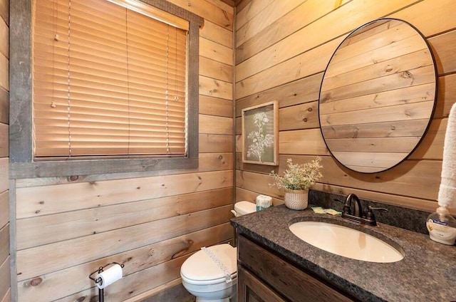 bathroom with vanity, toilet, and wood walls