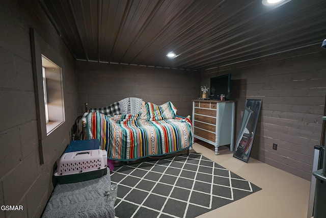 bedroom with finished concrete floors and concrete block wall