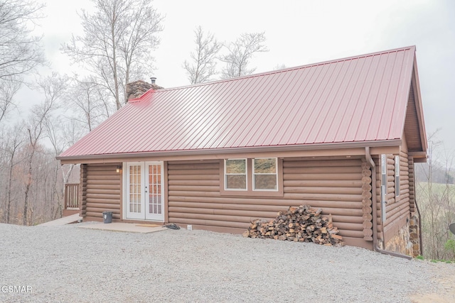 log home featuring metal roof, log exterior, french doors, and a chimney