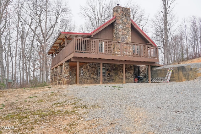 view of front of property featuring a wooden deck, stone siding, and a chimney