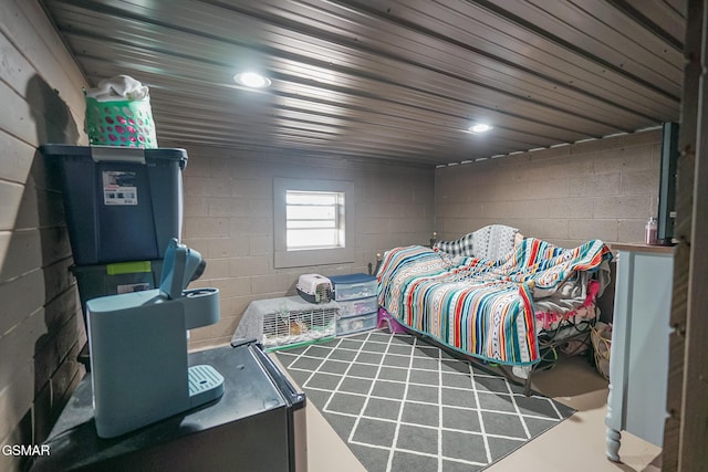 bedroom featuring recessed lighting, concrete block wall, and concrete flooring