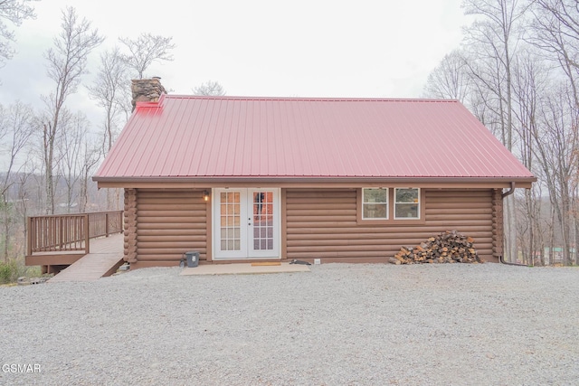 view of front of home with french doors, metal roof, log exterior, and a chimney