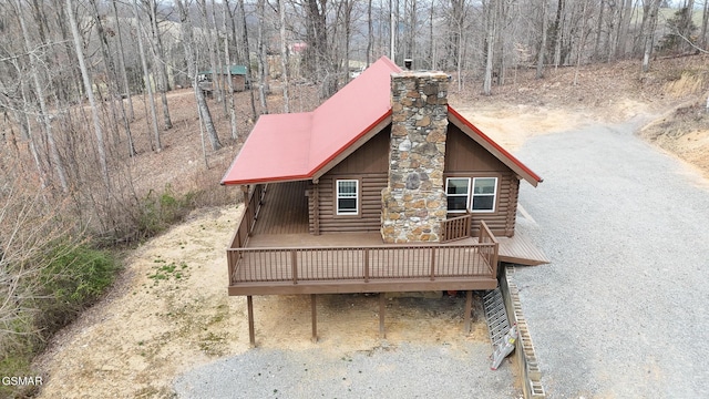 view of front of property with a wooden deck, log exterior, and a chimney