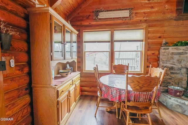 dining space with vaulted ceiling, wood finished floors, and log walls