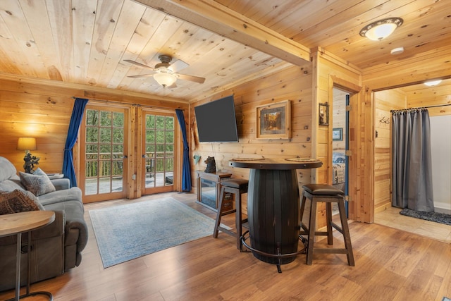 bar featuring ceiling fan, wooden ceiling, wooden walls, and light hardwood / wood-style flooring