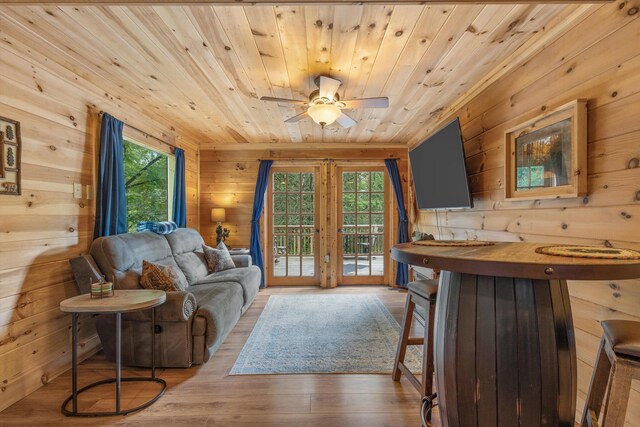 living room featuring light hardwood / wood-style flooring, ceiling fan, wood walls, and wood ceiling