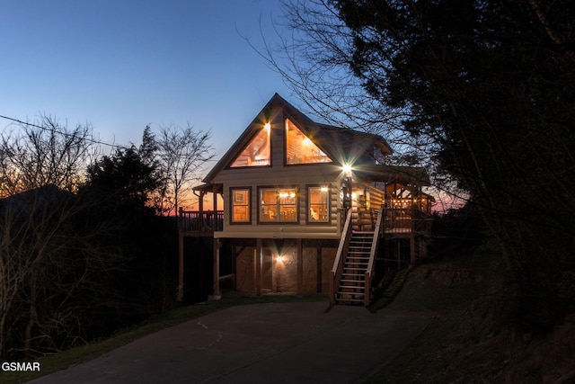 back of house at dusk with stairway and a deck