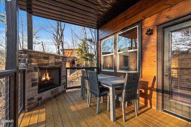 wooden terrace featuring outdoor dining space and an outdoor stone fireplace