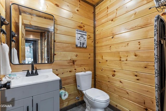 bathroom featuring toilet, wood walls, and vanity