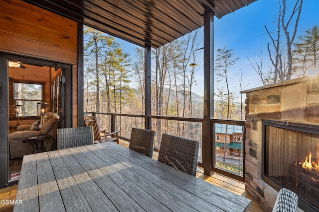 wooden terrace featuring outdoor dining area and an outdoor stone fireplace