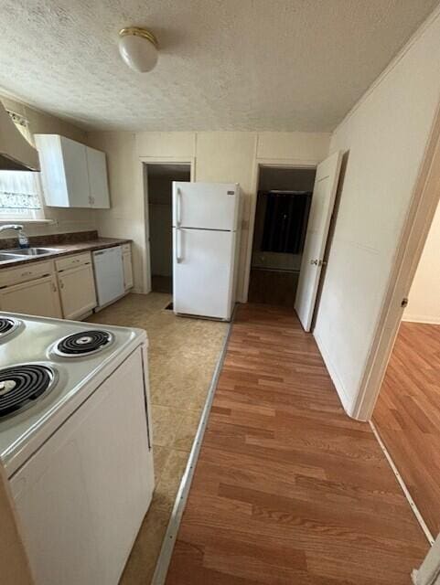 kitchen featuring sink, a textured ceiling, white appliances, white cabinets, and light wood-type flooring