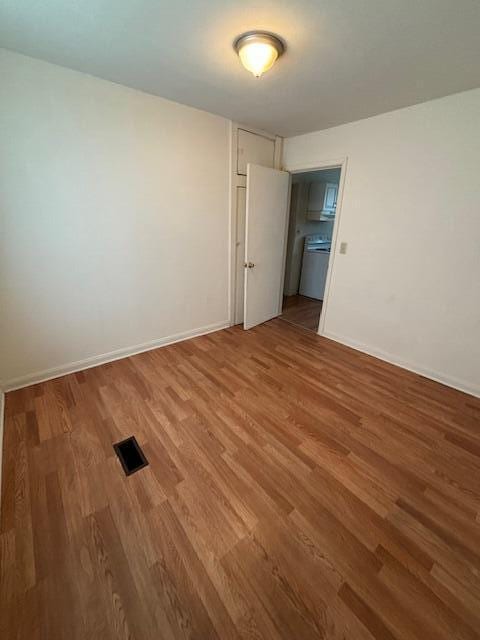 empty room with hardwood / wood-style flooring and washer / clothes dryer