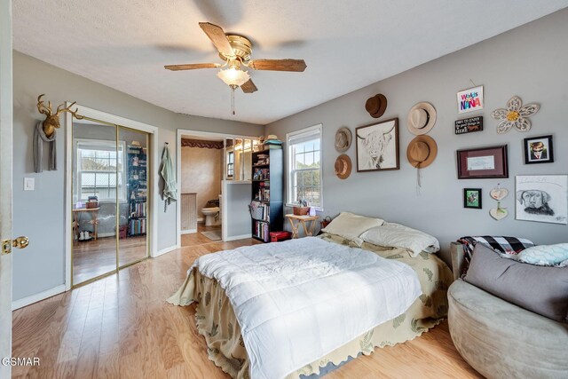 bedroom with ceiling fan, light hardwood / wood-style floors, and a textured ceiling