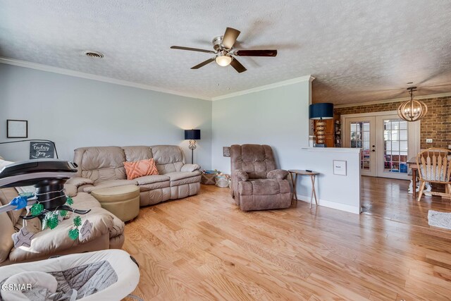 living room with french doors, light wood-type flooring, ornamental molding, a textured ceiling, and ceiling fan