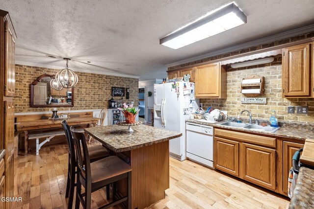 kitchen with brick wall, white appliances, pendant lighting, a chandelier, and light hardwood / wood-style floors