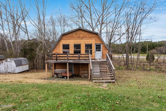 rear view of property with a wooden deck, a yard, and a shed