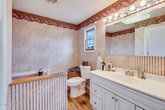 bathroom featuring a textured ceiling, vanity, hardwood / wood-style flooring, and toilet