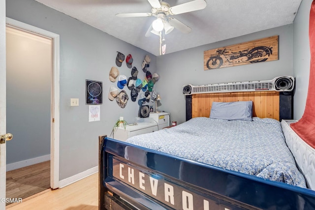 bedroom with ceiling fan, light wood-type flooring, and a textured ceiling