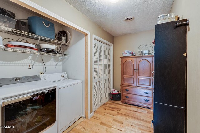 washroom with a textured ceiling, light wood-type flooring, and washing machine and clothes dryer